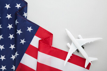 Toy plane with american flag on grey background. Travel concept