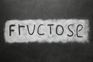 Word Fructose made of sugar on black table, top view