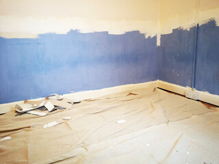 Corner of a bedroom during a home renovation project with a tarpaulin spread on the floor to prevent mess.