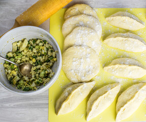 Process of making homemade pies with egg and onions, rolling pin for dough, on the kitchen table. Concept of making pies at home. Top and side view. Selective focus.