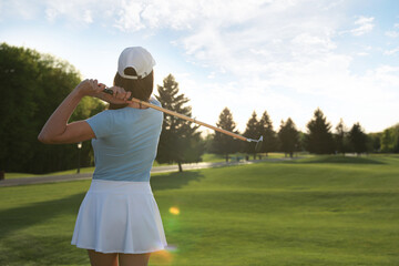 Woman playing golf on green course, back view
