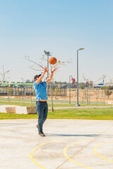 Front view of male playing basketball outdoor, public sport park.