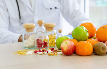 Fresh fruits, capsules and vitamins on desk. Nutritionist giving consultation to patient for nutrition and diet concept.