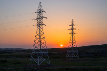 High tension tower with cables on the middle of Kazakhstan steppe at sunset time.