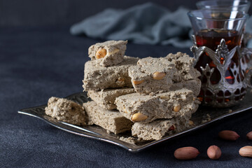 Sweet sunflower halva with peanut on metal tray on dark gray background. Close-up