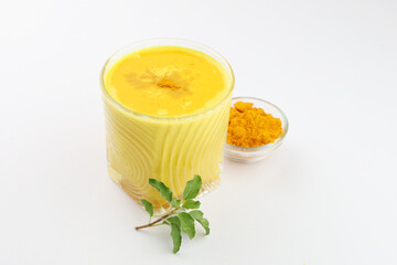 turmeric milk with turmeric powder and tulsi or holy basil on side