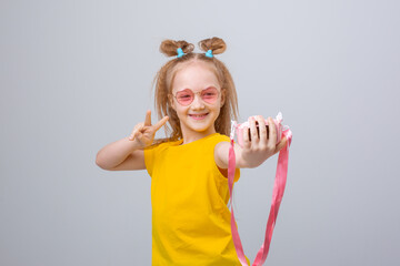 little girl in sunglasses traveler holds a camera on a white background