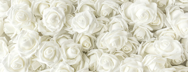 banner with background of many fake white roses. Top view.