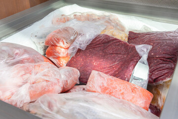Frozen food in the freezer. Bagged frozen meat and other foods in a horizontal freezer. Food...