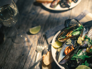 Blue mussles with vine and baguette on wooden table