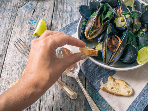 Blue mussles with vine and baguette on wooden table
