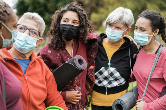 Multi generational women having fun before yoga class wearing safety masks at park outdoor - Sport and social distance concept - Main focus on center girl face