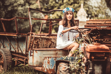 Fototapeta na wymiar Young Woman Sitting On Abandoned Vehicle At Field