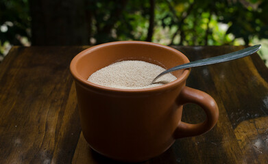yeast in grain, dried in a clay cup, with a metal spoon inside