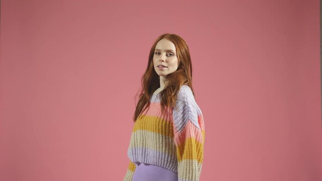 model in the studio poses for the camera, a portrait of a red-haired woman in a pullover on an isolated background
