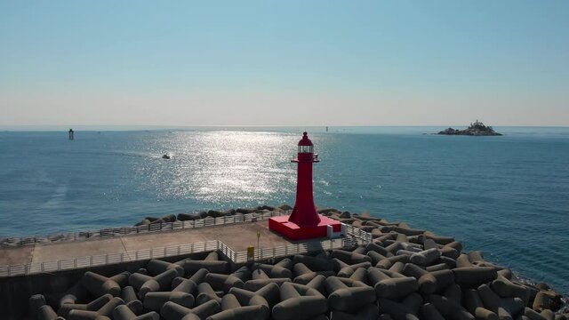 Sea surface is glittering reflects sun lights. Red lighthouse is on wave breakers. Beautiful nature aerial drone footage took with 4K 30fps.