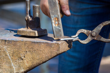 blacksmith performs the forging of hot glowing metal on the anvil