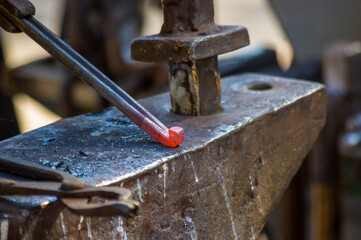 blacksmith performs the forging of hot glowing horseshoe on the anvil