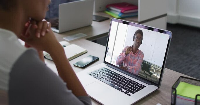 African american woman having a video conference on laptop with male office colleague at office