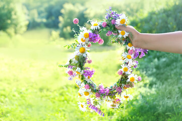 wreath of meadow flowers in hand. Summer Solstice Day, Midsummer concept. floral traditional decor....