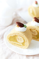 Banana Swiss Roll Cake with banana cream filling set on white cafe table.