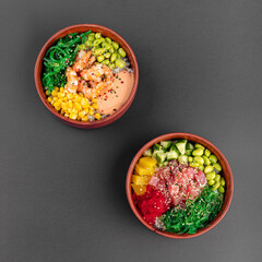 Two bowls of hawaiian poke mix with tuna fish and shrimp on grey background