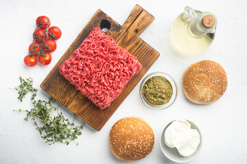 Fototapeta na wymiar Home Raw Minced Beef Meatball burgers ingredients, on wooden cutting board, on white stone background, top view flat lay