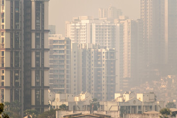 A hazy skyline of suburban Mumbai with a highrise skyscrapers in a dense, congested neighbourhood.