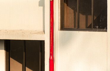 A red water pipeline and windows of houses on the walls of a high rise building in suburban Mumbai.