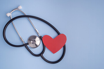 A stethoscope and red paper a heart shape isolated on a light blue background. Close-up photo. Top view. Flat lay with Space for text. Healthcare and medicine concept