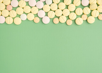 Pile of tablets medicine for people's health to heal diseases isolated on a green background. Space for text. Top view. Healthcare and medical concept