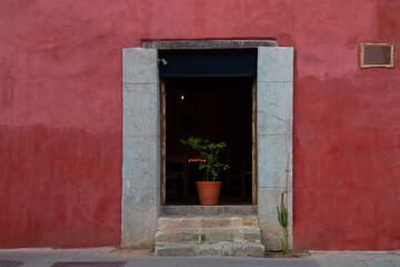 Red facade of a house with a colored wall. Colorful empty colonial street in Mexico. 