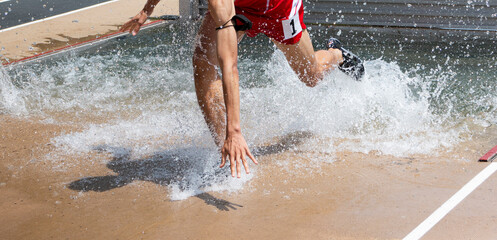 Steeplechase runner falling in the water during a race