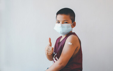 Asian boy showing his arm after getting covid-19 vaccine.