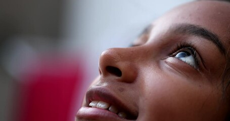 Preteen girl eyes looking up at sky smiling, Black African descent
