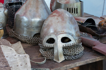 an old knight's helmet with scratches and dents lies on a wooden table