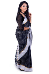 Young Indian woman wearing an elegant black saree. Looking at camera. Smiling. Happy. Grey background. Full length shot