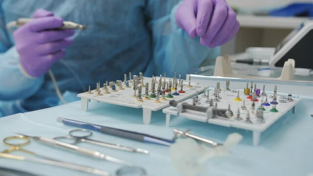 Close-up of a dental surgeon preparing a working tool for implanting a tooth to a patient.