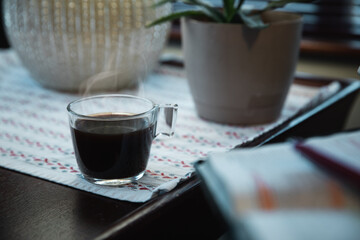 Early morning steaming cup of coffee and out of focus Bible and journal