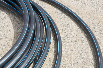 Black polyethylene pipes on a urban road of a construction site with new hydraulic system of drinking water to be carried out under the road surface level