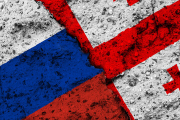 Concept of a Conflict between Georgia and Russia with painted flags on a wall with a crack