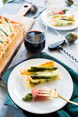 Step by step  recipe preparation of an asparagus and speck tart made with egg yolk, cream , parmisan , brisee pasta, speck and asparagus. prepared cooked and served, top view, flatlay composition