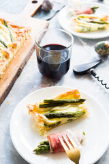 Step by step  recipe preparation of an asparagus and speck tart made with egg yolk, cream , parmisan , brisee pasta, speck and asparagus. prepared cooked and served, top view, flatlay composition