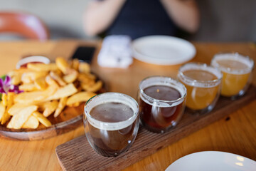 Man sampling variety of seasonal craft beer in pub. Beer samplers in small glasses individually placed in holes fashioned into unique wooden tray. Selective focus with shallow depth of field.