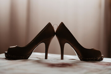 Tacones de novia sujetando alianza a contra luz