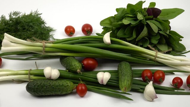 Cherry tomatoes, cucumbers, green onion, dill, spinach, garlic are on a white table, salad ingredients