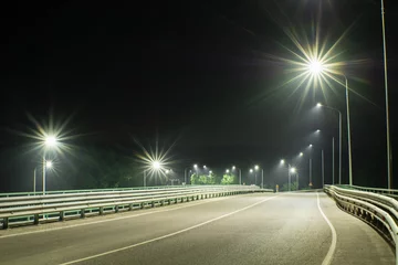  An empty country road with bumpers at the edges, lit by streetlights © VeNN