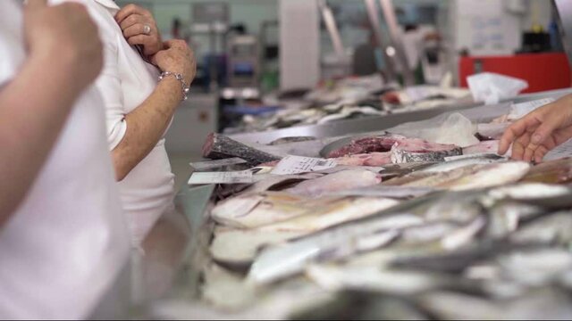 old lady chosing fish and seller grabbing the fish