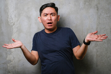 Young Japanese man wearing navy casual clothes clueless and confused with open arms, no idea and...