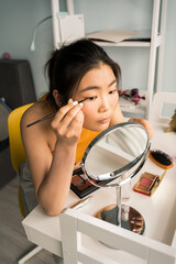 Woman with brunette hair making daily makeup at home at the bedroom